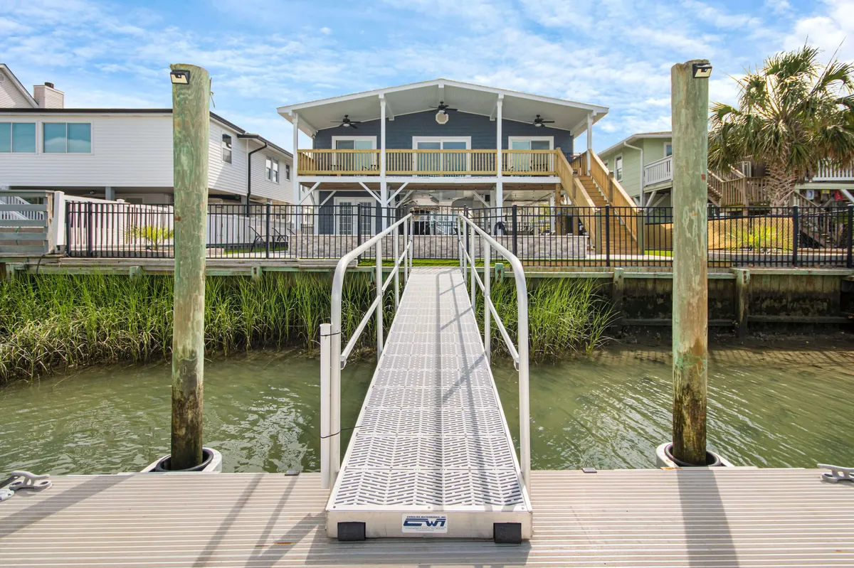 This cheerful exterior scene displays the home's dock, the house itself, and lush greenery. The setting is lively, ideal for family gatherings, water activities, and outdoor barbecues, while the proximity to the water and house connects the home's amenities with the broader Cherry Grove neighborhood experience.