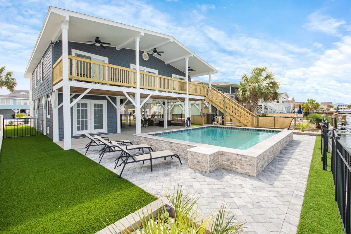 The hero image showcases a sparkling private swimming pool surrounded by a spacious deck with comfortable outdoor seating, lush landscaping, and a well-maintained lawn. The scene suggests opportunities for sunset swims, lively barbecues, and relaxing evenings with friends or family.