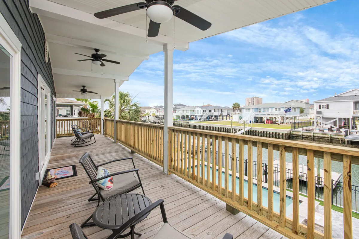 A cozy, well-appointed wooden deck with comfortable chairs and ceiling fans, all oriented towards a sweeping waterfront view. The setting is perfect for enjoying a sunrise coffee or unwinding at sunset, with a tranquil, inviting atmosphere that feels both luxurious and personal.