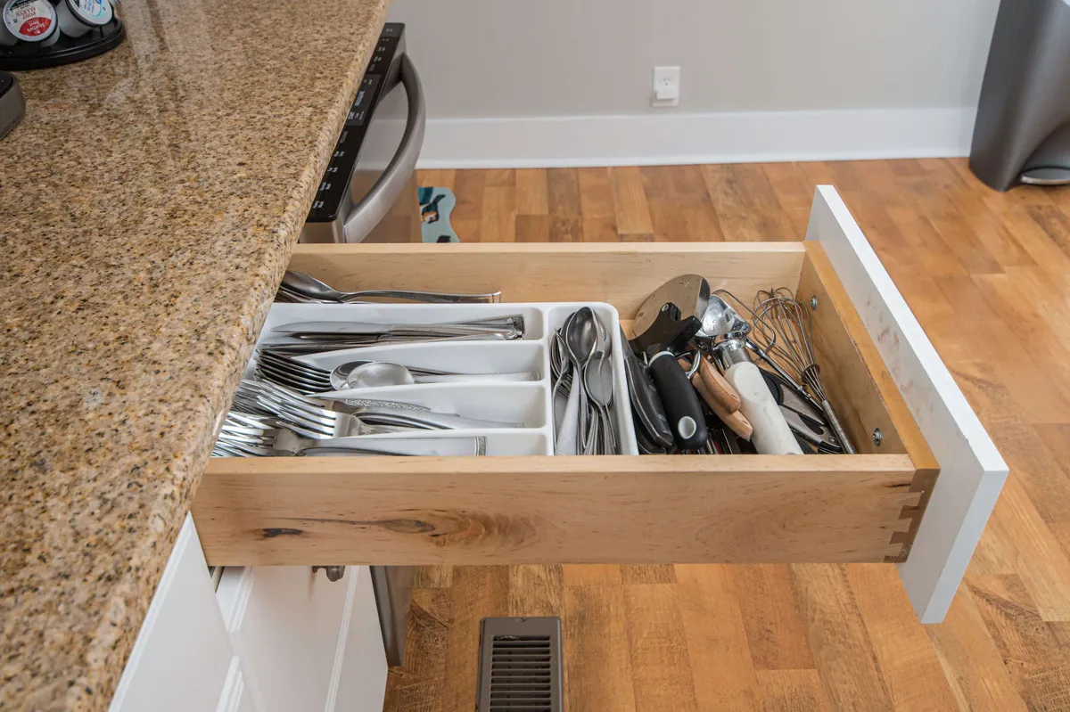 A close-up of a sleek granite countertop in the kitchen, with an organized kitchen drawer displaying cutlery. The modern finishes and functional setup highlight the gourmet aspect of the kitchen, reinforcing the updated, comfortable feel of the home.